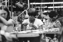 Women operate sewing machines in a garment shop.