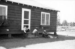 Men lounge in the shade of a building at Delta Cooperative