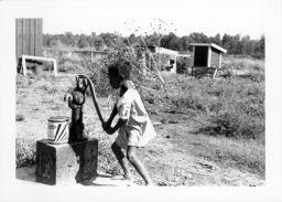 A young, black girl pumping water at Delta Cooperative.