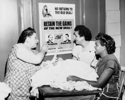 Women in front of a campaign poster, discussing Adlai Stevenson.
