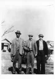 E.B. McKinney, STFU Vice President (left), standing with two unidentified men, one of whom holds a gun