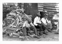 Three Black men sit on a wood pile during a STFU meeting