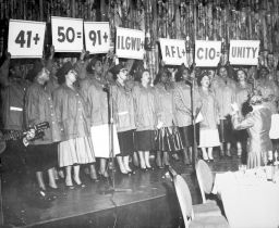 ILGWU Local 91 chorus holds up signs reading, "41 + 50 = 91+ ILGWU+ AFL+ CIO = UNITY"