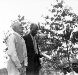 A minister and another man on the platform, possibly singing, during an outdoor STFU meeting