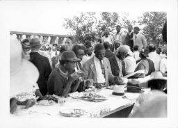 Large group sharing a meal at outdoor banquet tables during an STFU meeting