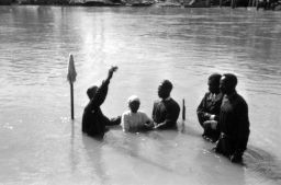 Young child is baptized in the river assisted by 4 men