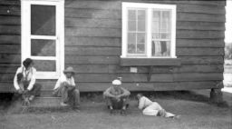 Men lounge in the shade near a building at Delta Cooperative