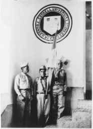 Three school boys in cadet uniforms with Peruvian flag, Cornell seal in background