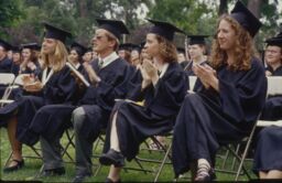 A row of graduates clap during Commencement