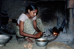 Householder at fire pit preparing yams