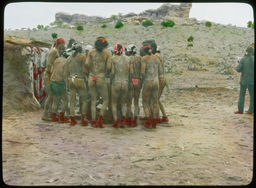 A small group of men in loincloths, huddled together