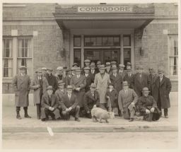 Group of men with a child and a sheep outside a building labeled Commodore in Livingston or Wyoming County, NY.