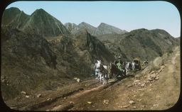 A small group of Japanese individuals move through a strikingly mountainous terrain