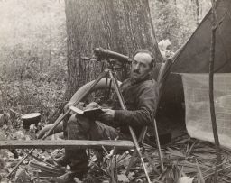 Arthur Allen seated, writing in journal, telescope behind him
