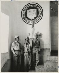 Three school boys in cadet uniforms with Peruvian flag, Cornell seal in background
