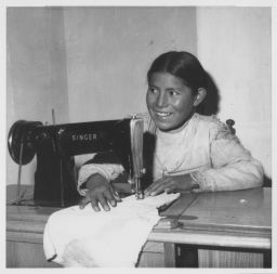 Young woman sewing yard goods on machine
