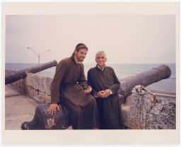 Daniel Berrigan and another man standing next to a canon while on a Mission Trip