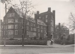 Front of Prudence Risley Hall, viewed from northeast with Thurston Ave. in the foreground and four women walking toward the entrance.