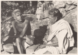 Village elders seated at rest area along main village path near garden