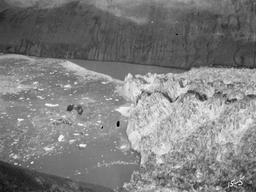 Front of Nunatak Glacier from crest of Nunatak (1350 ft). Berg just fallen, above black shot.