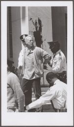 Philip Berrigan in handcuffs in front of dirtied column