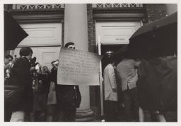 Protester standing outside Bailey Hall with a sign.