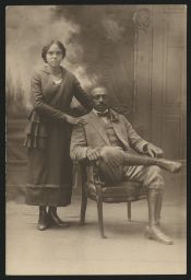Woman standing next to seated man