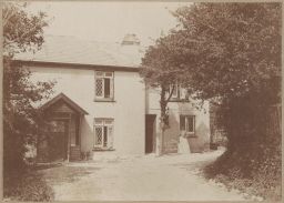 Unidentified woman with bird cage in front of Knap Cottage.