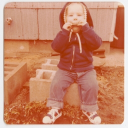 Toddler Honey Lee Cottrell playing harmonica outside.