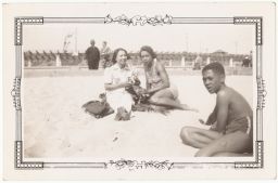 Women and boy sitting on the beach with a dog