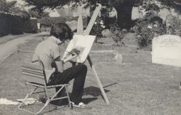 Photograph of young Lindsay Cooper painting in a graveyard