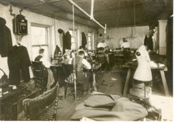 Several men sewing garments in factory setting