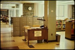 Information / reference desk in front of filing cabinets, reference books, and Alfred W. Smith Browsing Library.