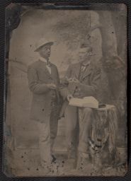 Two men posed with book and open pocket watch