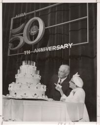 Benjamin R. Andrews, first secretary-treasurer of the AHEA, and Mary Sweeney, AHEA 1920-22, admire the birthday cake at the 50th Anniversary luncheon of the Association