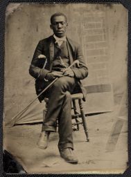 Man seated on stool with cane