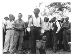 An early union meeting. Black and White STFU members including Myrtle Lawrence and Ben Lawrence, listen to Norman Thomas speak outside Parkin, Arkansas on September 12, 1937. One man carries an enamel pot and drinking glass.