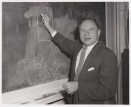 Philip Morrison writing on a chalkboard