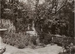 Garden, partial view of a sundial, bench and a wall at the rear