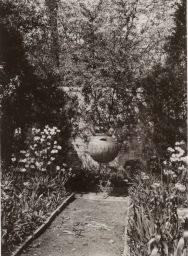 Garden with raised flower urn and wall at rear