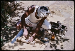 Carpenter with tools making a stool in courtyard