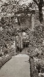 Garden path leading to an arched entrance gate at one end of front porch