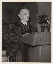 William Stringfellow at a podium in university gown