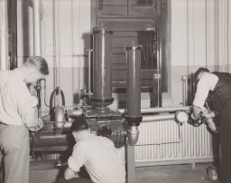 Three Men working on refrigeration equipment in Roberts Hall basement