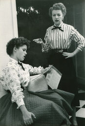 Betty Furness – standing and talking with young woman reading in a chair