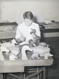 Student painting wooden ducks