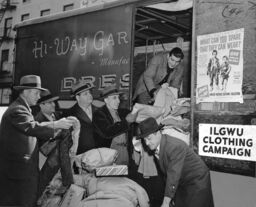 ILGWU Clothing Campaign, part of the United National Clothing Collection displays a poster "What can you spare that they can wear?" while loading clothing into a truck