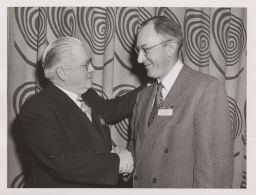 Paul G. Oppermann shaking hands with an unidentified man