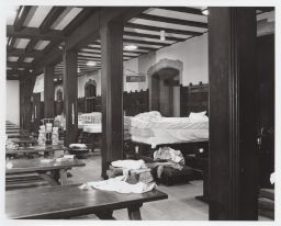 Closer view of mattresses and bedding piled on tables in Willard Straight dining hall.