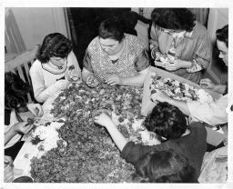 Women, young girls, and boys making artificial flowers at home on their kitchen table